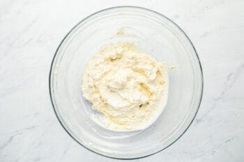 cream cheese, mayo, sour cream, and spices mixed together in a glass bowl.