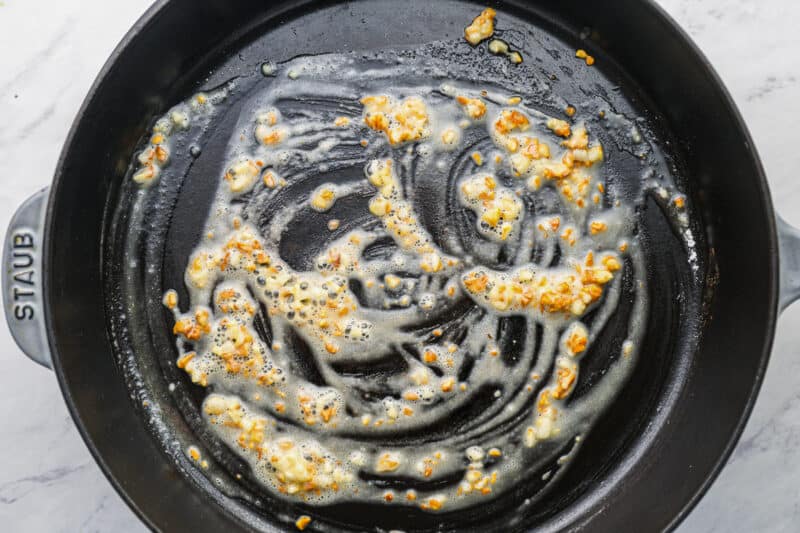 butter and garlic cooking in a cast iron pan.