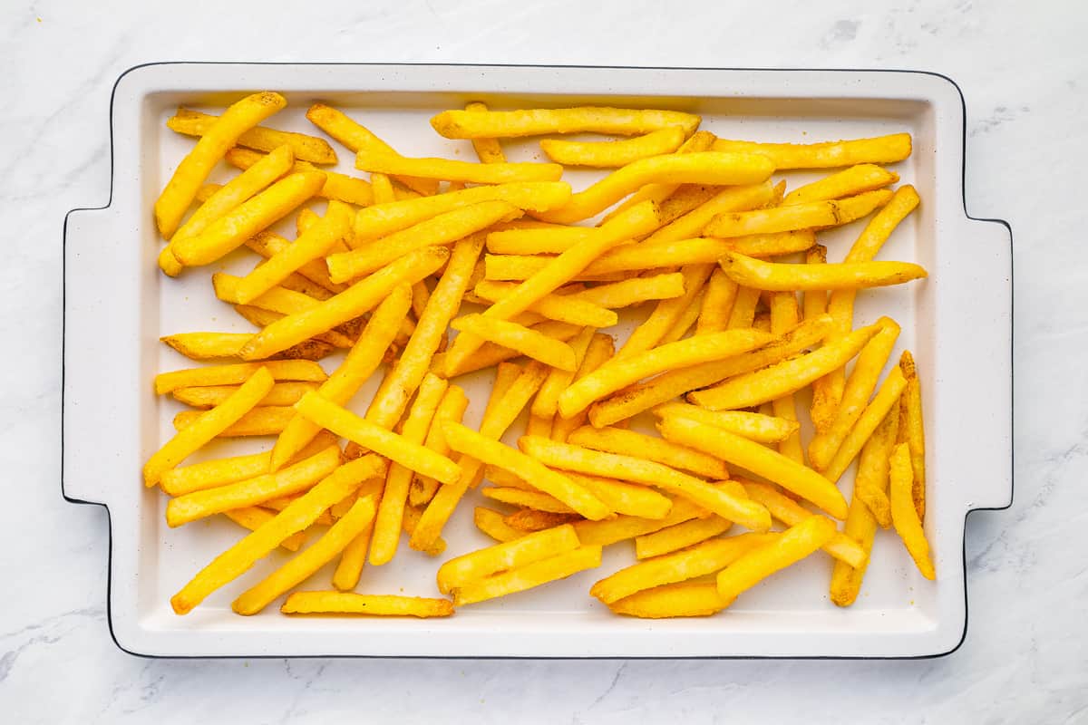 Baked frozen French fries on a white rectangular serving tray.