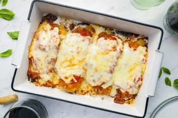 baked chicken parmesan in a white rectangular baking pan with fully melted cheese.