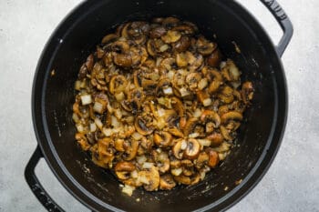 flour sprinkled over mushrooms onions and garlic in a dutch oven.