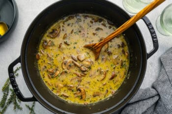 mushroom soup in a dutch oven with a wooden spoon.