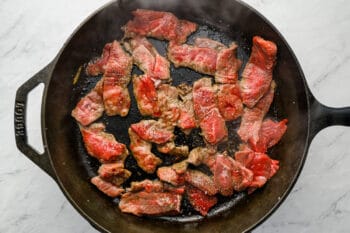 steak cooking in a cast iron pan.
