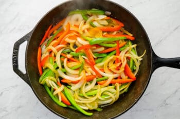 sauteed peppers and onions in a cast iron pan.