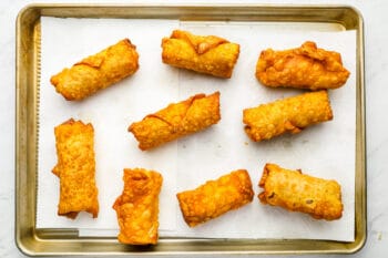 overhead view of 9 reuben egg rolls on a baking sheet.