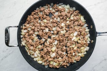 cooked ground beef and onions in a frying pan.