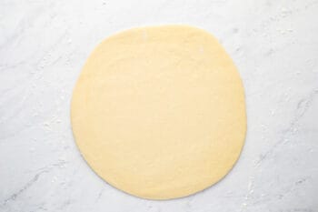 pizza dough rolled out into a 12 inch circle.
