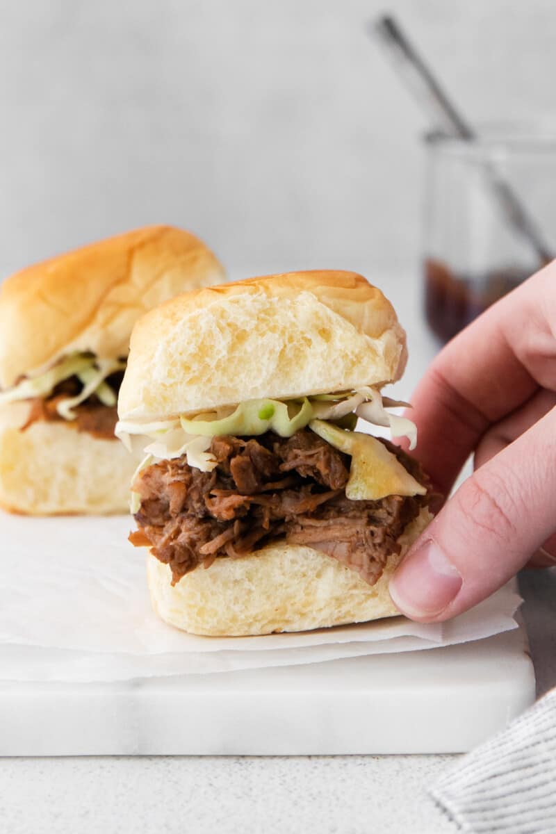 hand lifting up slider with pulled pork