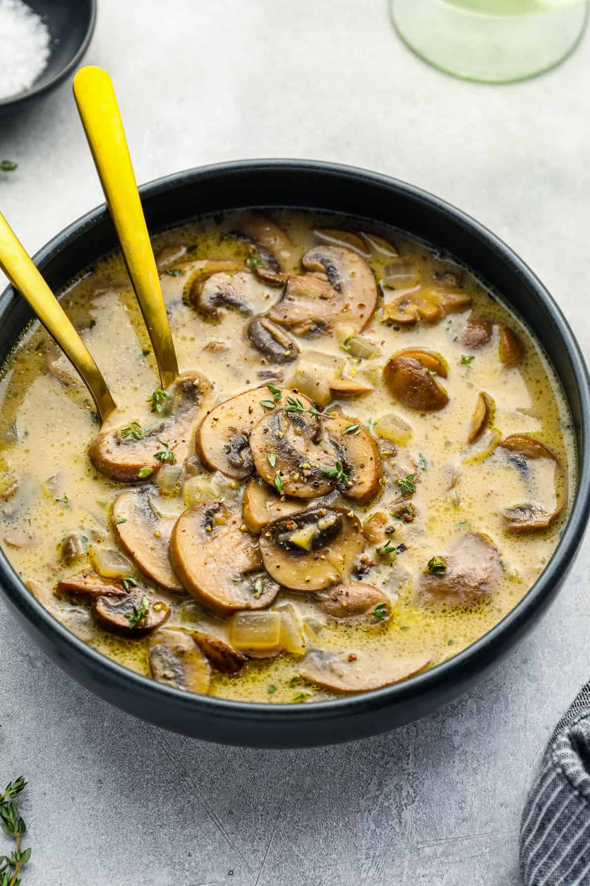 mushroom soup in a black bowl with 2 spoons.