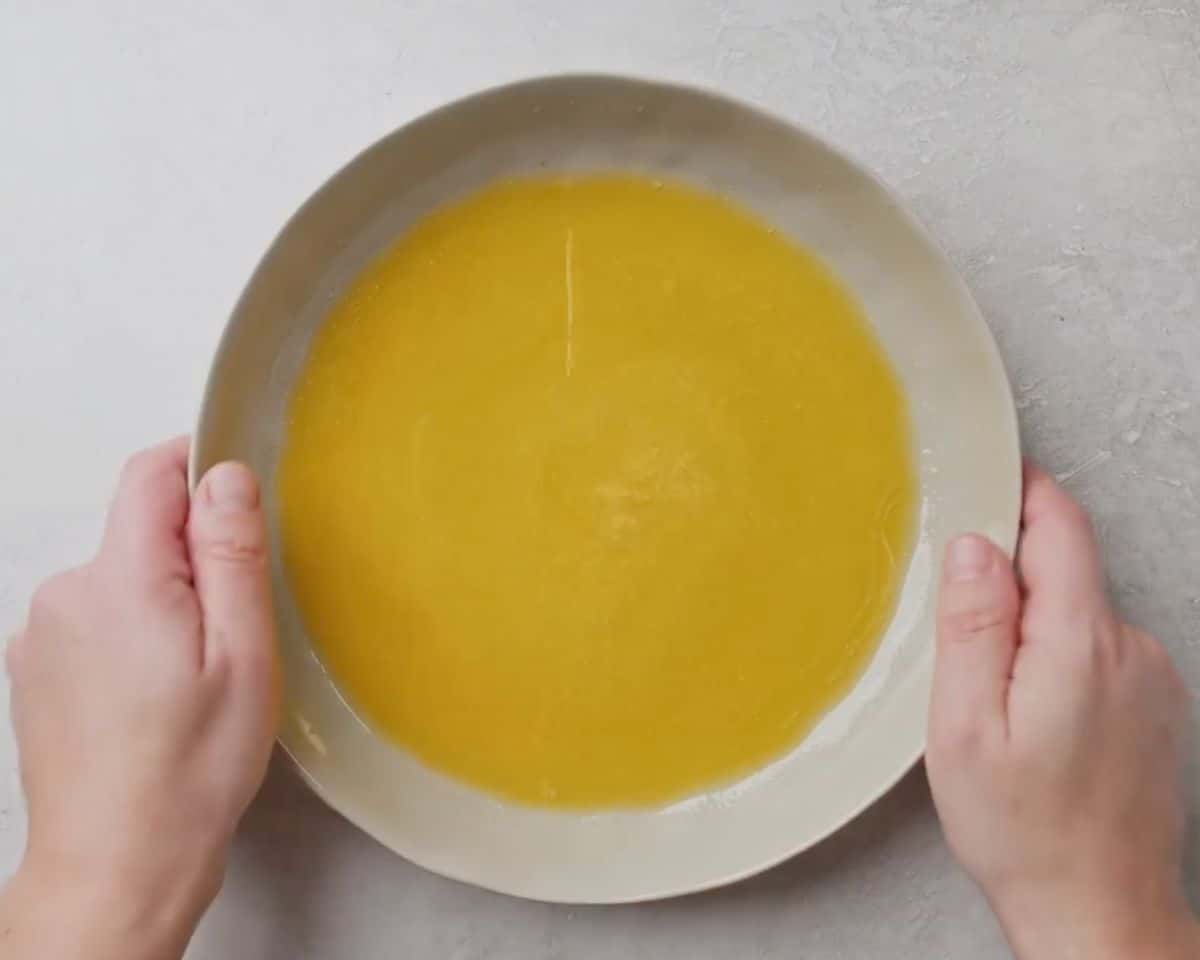 Melted butter mixture in a shallow bowl for coating parmesan crusted chicken before baking