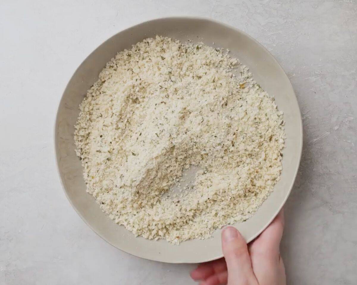 Parmesan and panko breadcrumb mixture in a bowl for crispy oven-baked chicken coating