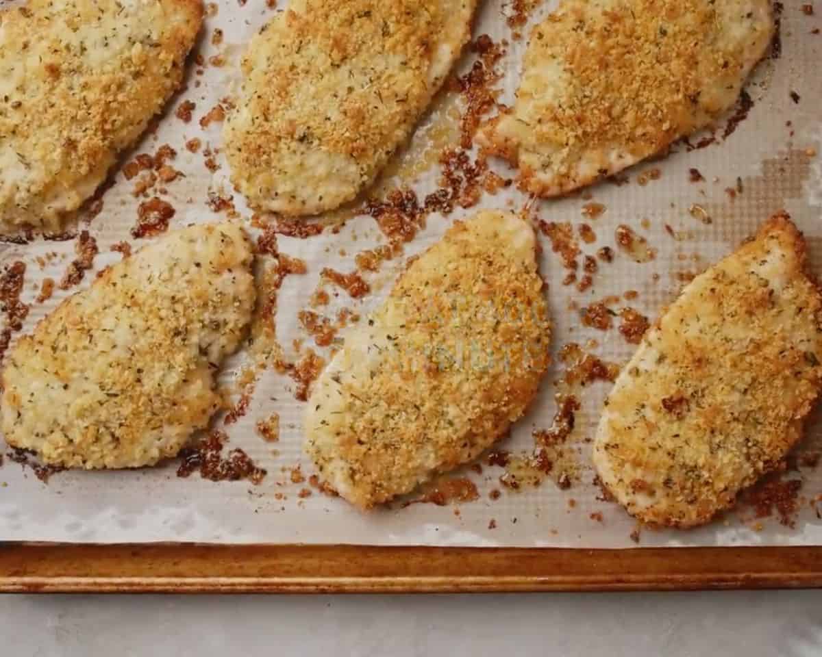 Oven-baked parmesan crusted chicken on a baking sheet with a golden, crispy coating
