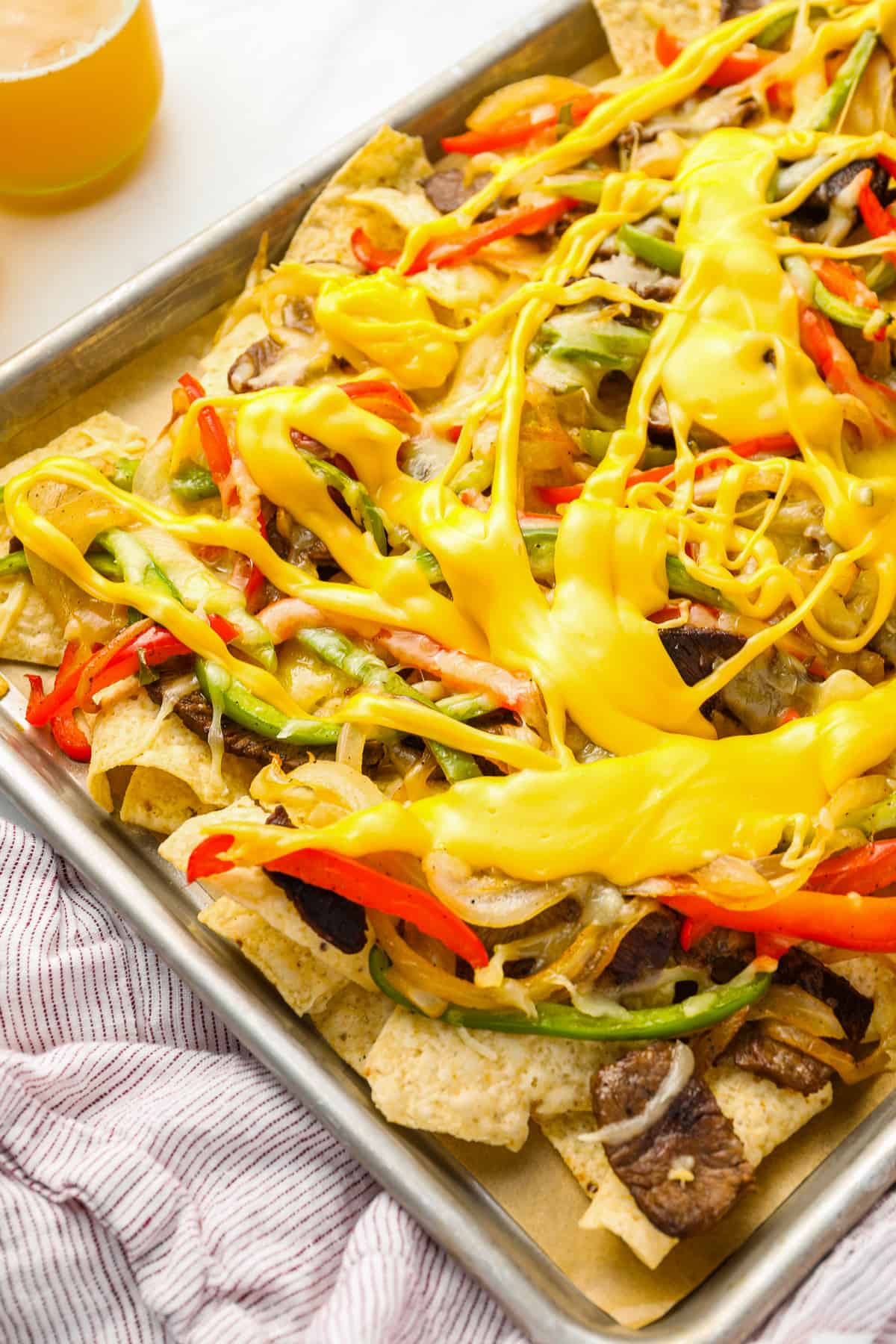 partial view of philly cheesesteak nachos on a baking sheet.