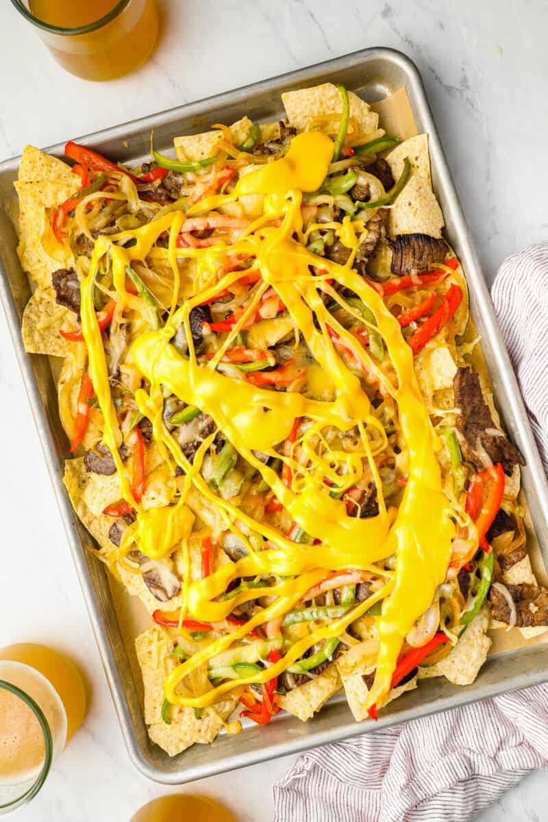 overhead view of philly cheesesteak nachos on a baking sheet.