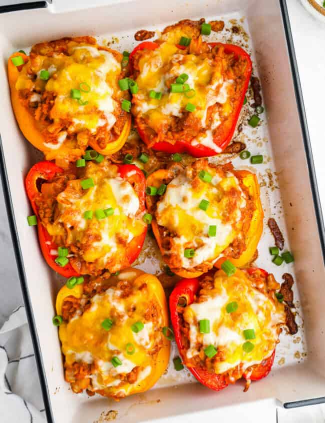 overhead view of 6 stuffed peppers in a white rectangular baking pan.