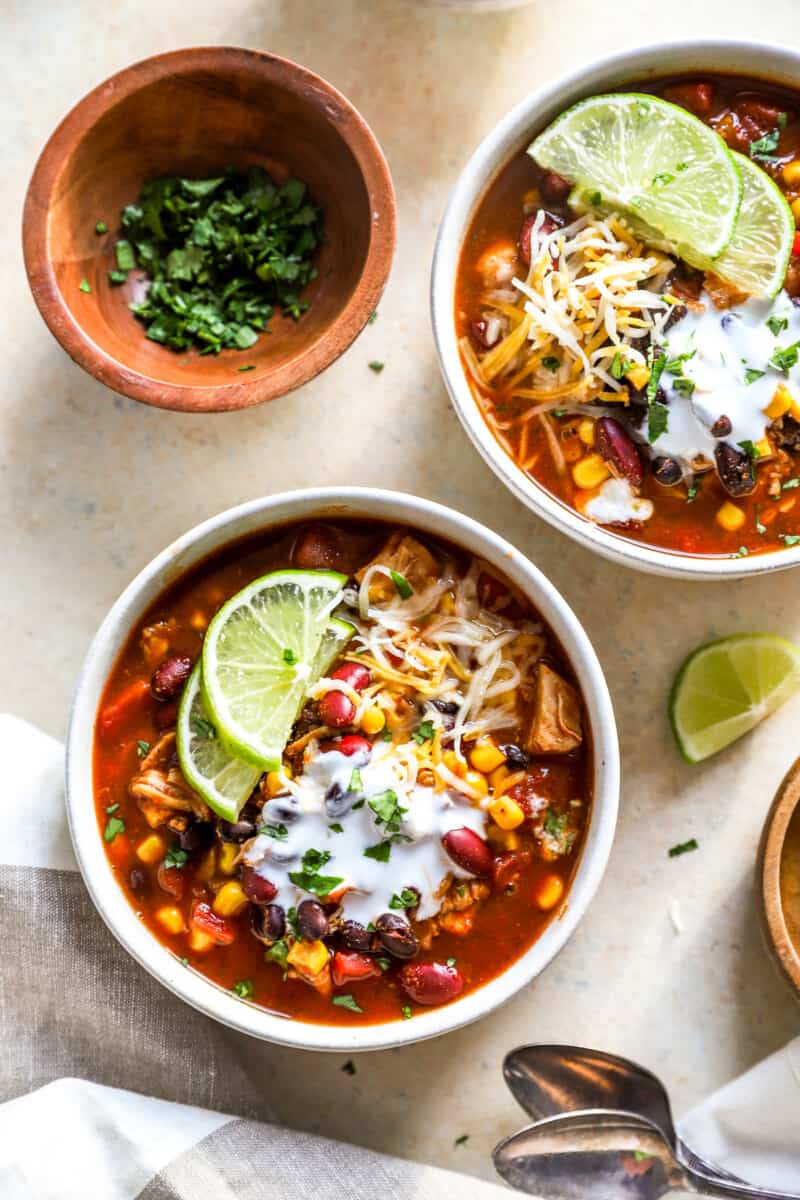 overhead view of 2 bowls of 7 can soup with lime wedges and cheese.