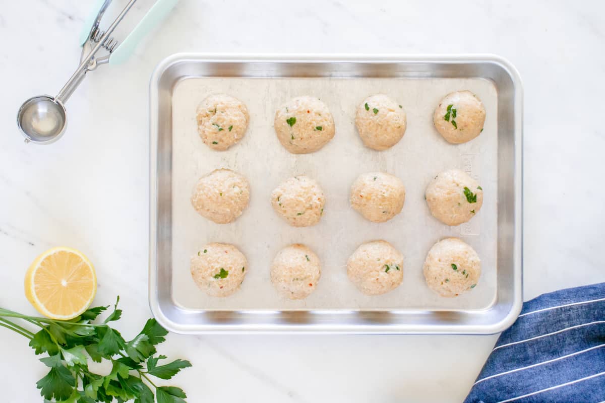 12 chicken piccata meatballs on a rimmed baking sheet.