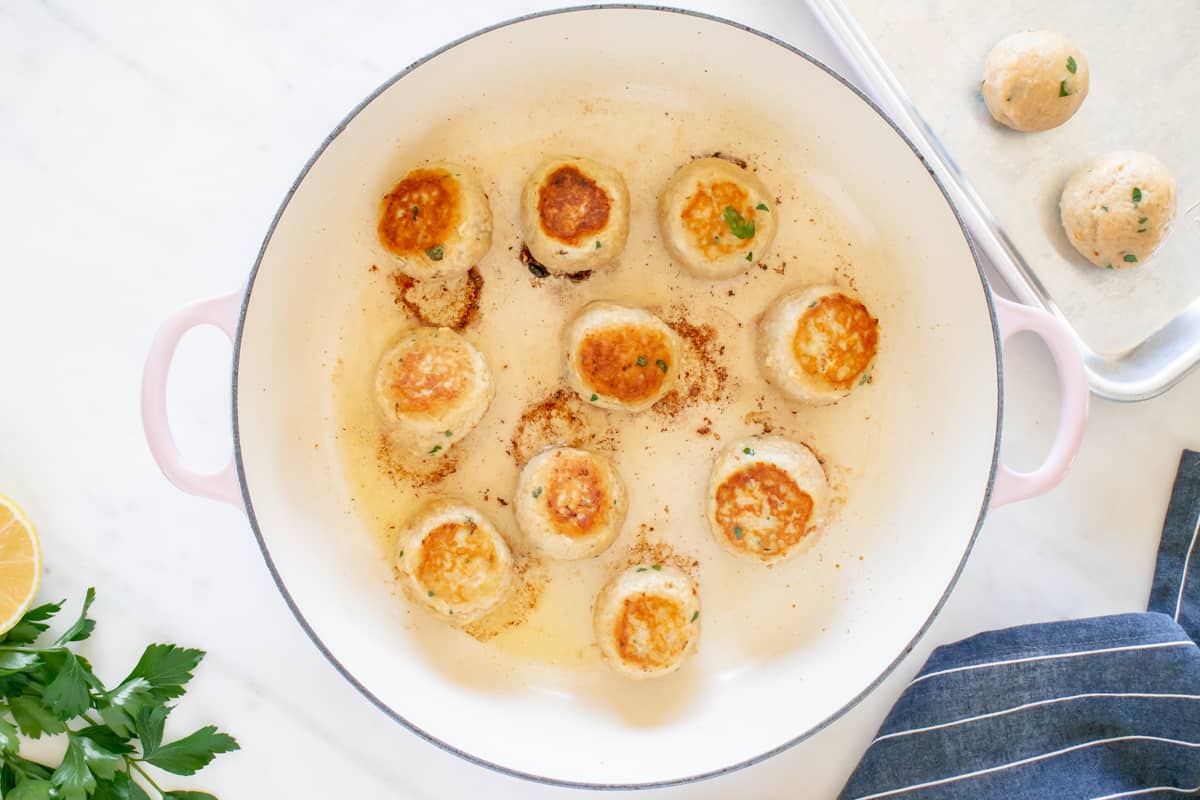 a pan full of fried scallops with lemon and parsley.