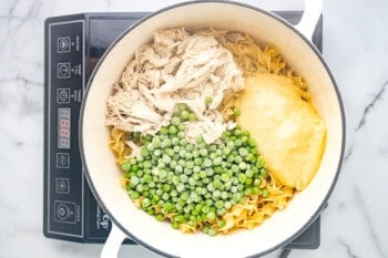 peas, chicken, and cream of chicken soup added to noodles in a dutch oven.