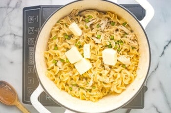 butter added to chicken and noodles in a dutch oven.