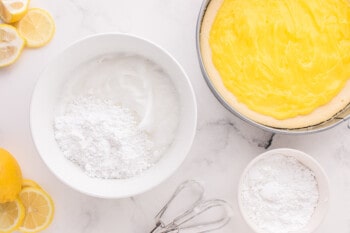 sugar added to whipped egg whites in a white bowl.