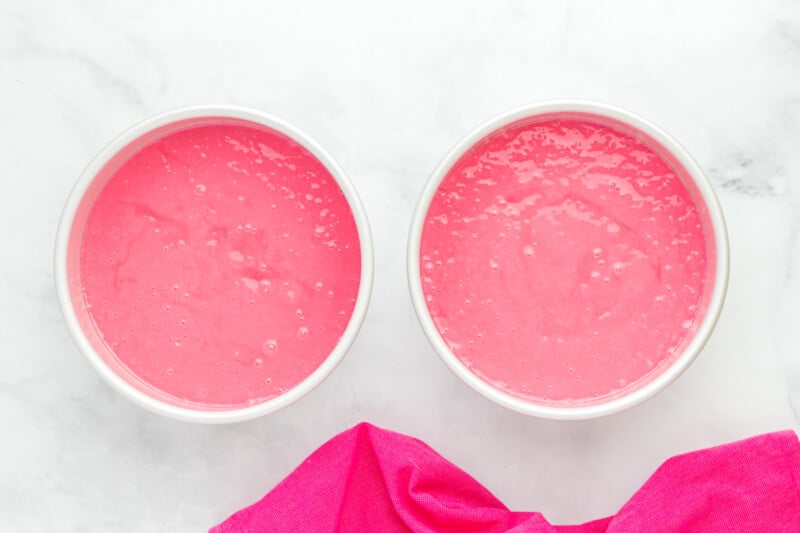 pink velvet cake batter divided between 2 round cake pans.