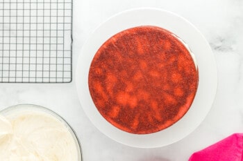 overhead view of a pink velvet cake layer on a white cake stand.