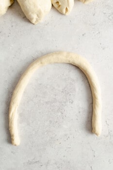 a log of homemade pretzel dough log in a semicircle shape.