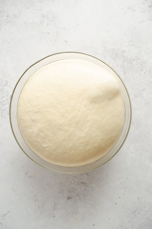 proofed homemade pretzel dough in a glass bowl.