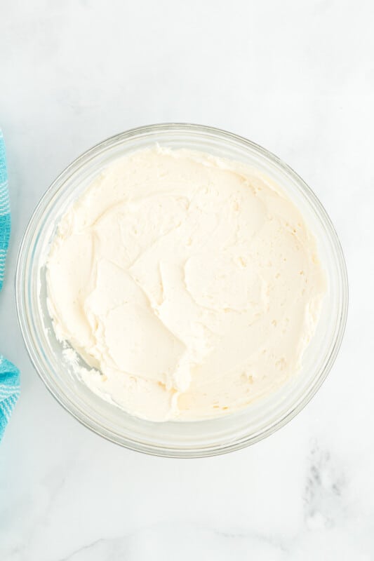 overhead view of white frosting in a glass bowl.