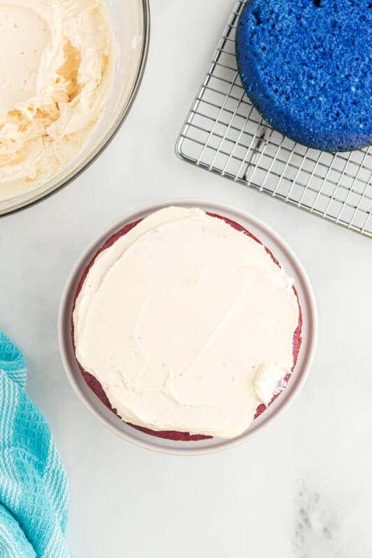 overhead view of a frosted purple cake layer on a white cake stand.