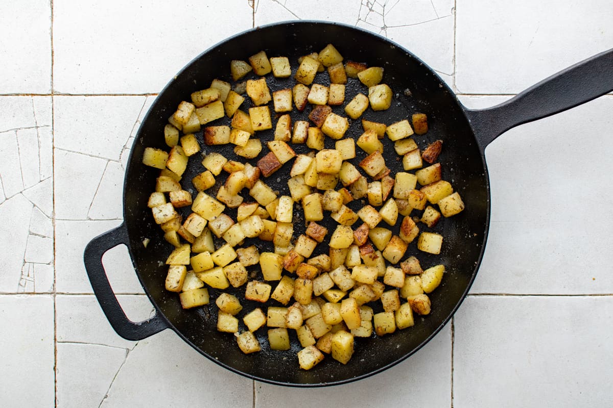 crispy cubed potatoes in a cast iron skillet.