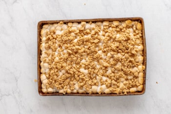 graham cracker crumble added to smores bars in a rectangular baking pan.