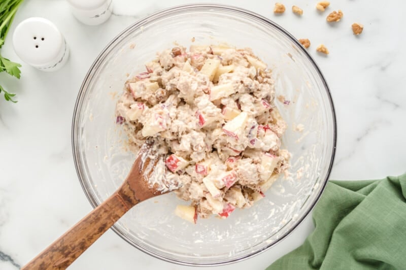 tuna salad in a white bowl with a wooden spoon.