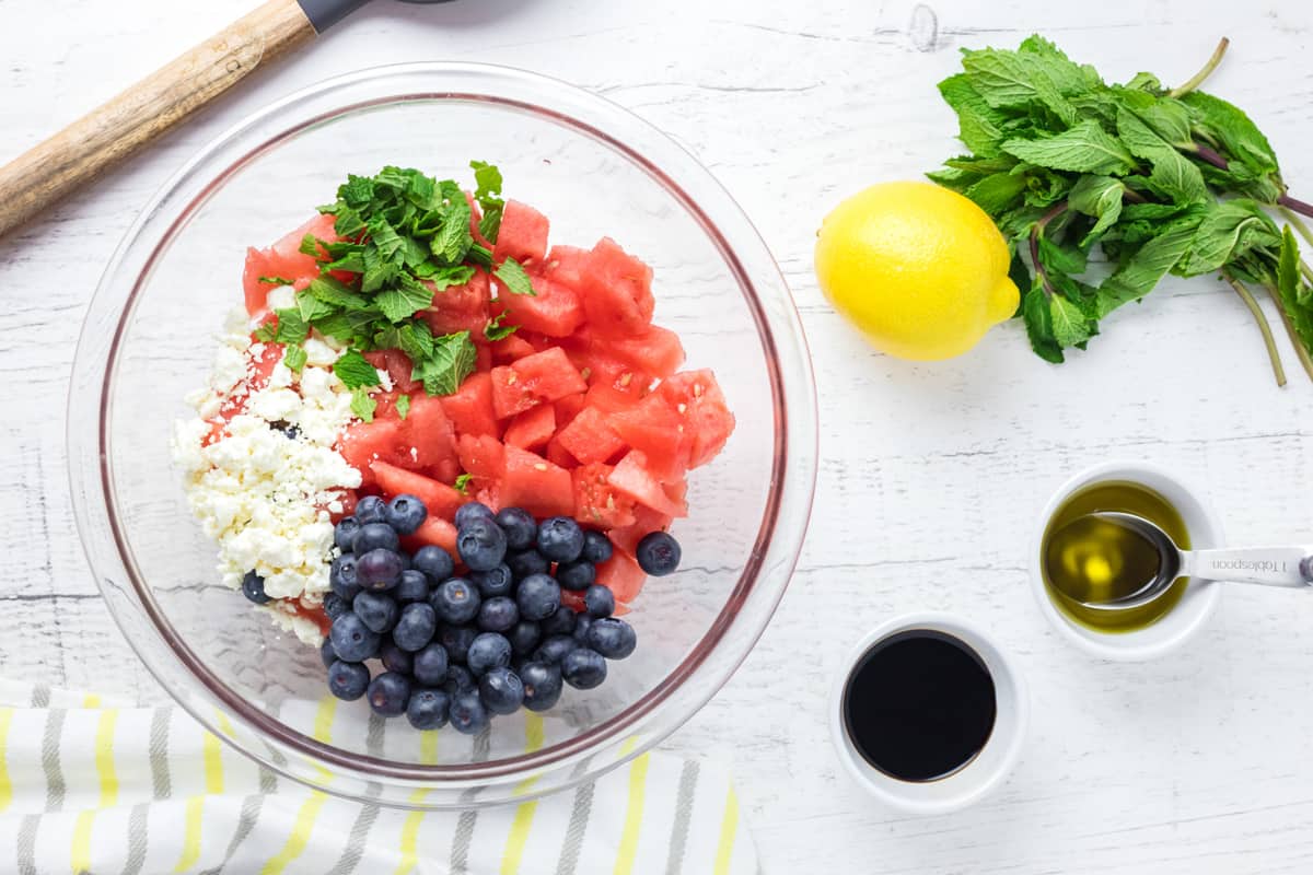 watermelon, blueberries, mint, and feta cheese in a glass bowl.