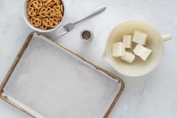 a baking sheet with butter, pretzels and pretzel sticks.