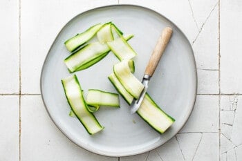 zucchini cut into ribbons on a white plate.