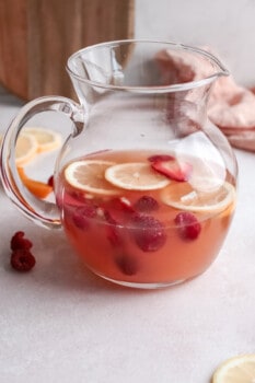 rose sangria in a large glass pitcher with fruits.