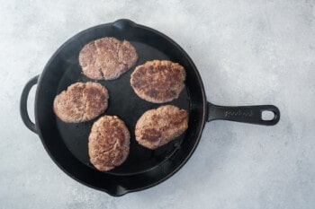 5 salisbury steaks in a cast iron pan.
