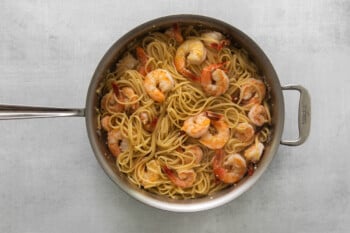 pasta and shrimp tossed together in a frying pan.
