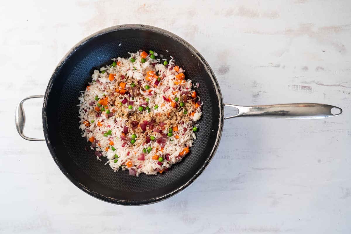 veggies and rice mixed together in a wok.