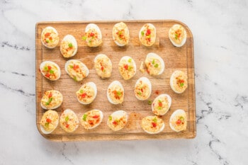overhead view of pimento cheese deviled eggs on a wooden cutting board.