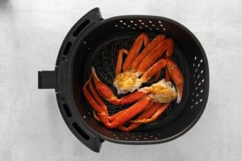 crab legs in an air fryer basket.
