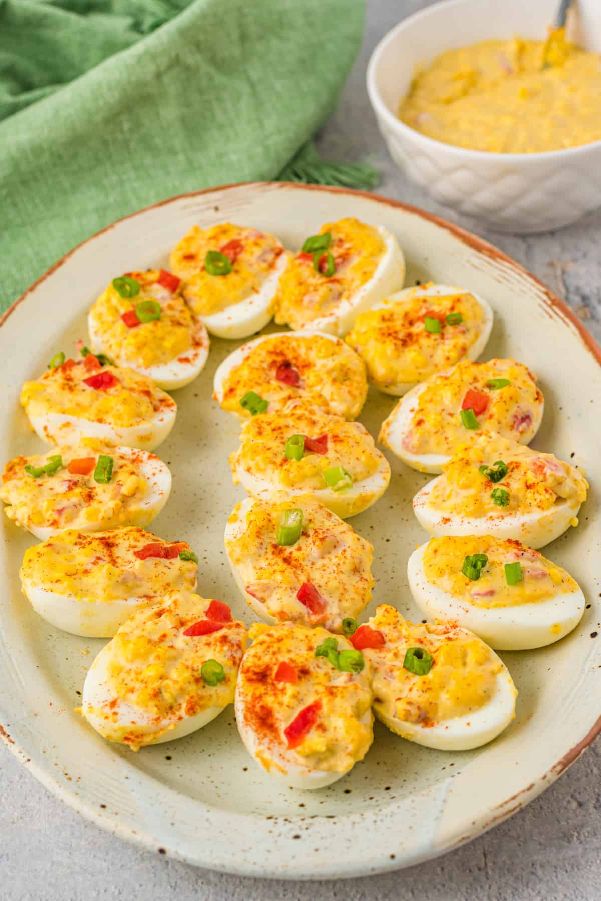 three-quarters view of pimento cheese deviled eggs on a white oval serving tray.