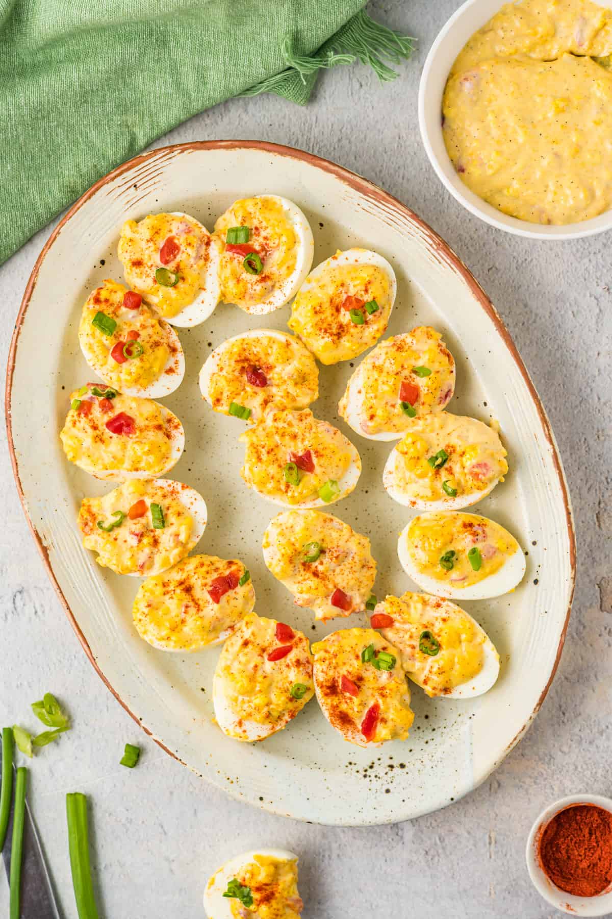 overhead view of pimento cheese deviled eggs on a white oval serving tray.