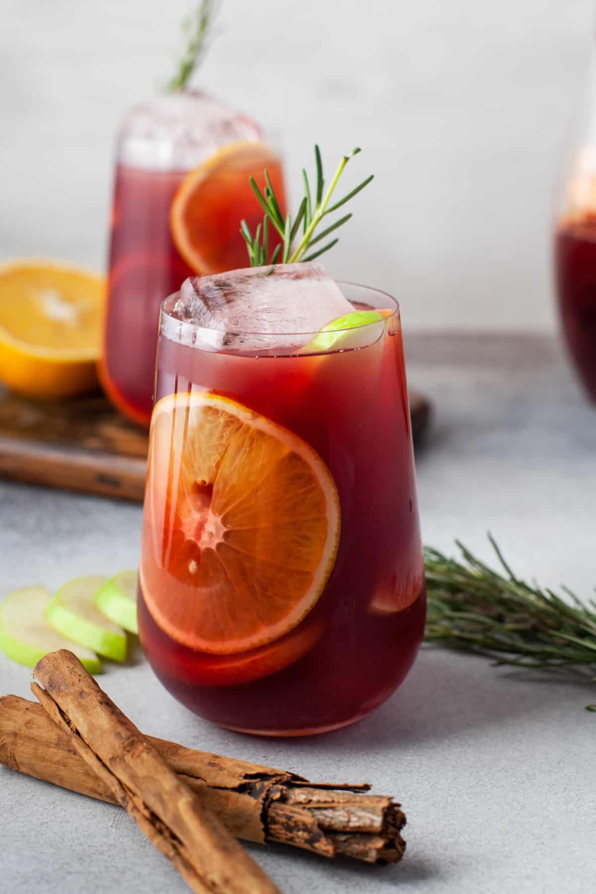 side view of red sangria in a stemless wine glass with ice and rosemary.