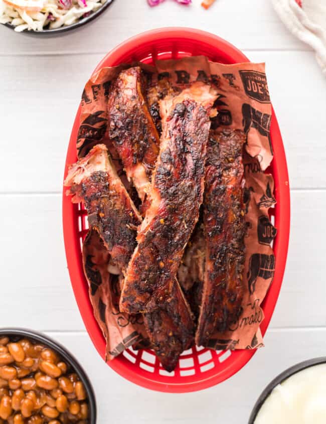 overhead view of smoked ribs in a red plastic basket.