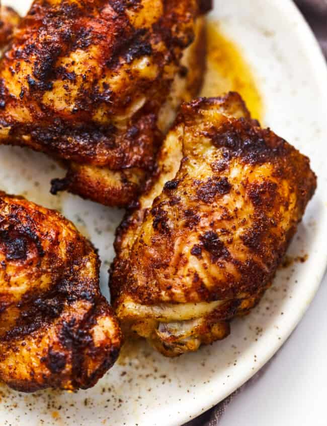 3 air fryer chicken thighs on a white plate.