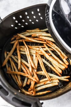 cooked air fryer french fries in an air fryer basket.