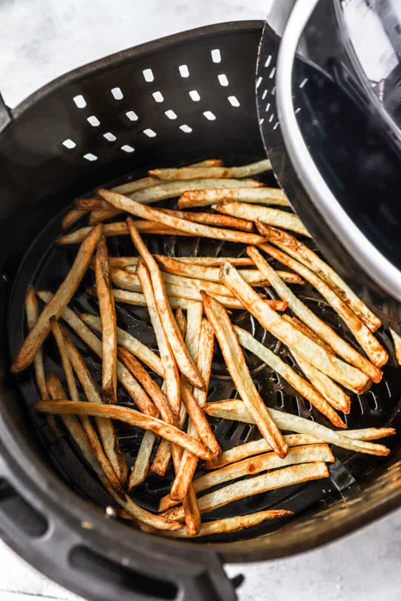 Cooked air fryer French fries in an air fryer basket.